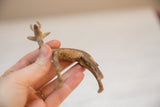 Vintage metal gazelle held to show its handmade texture and aged golden patina.