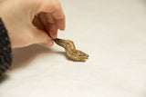 Side view of the vintage African snake pendant highlighting its handmade, spotted texture.
