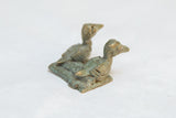 The aged green patina and handmade texture of the vintage African bronze bird figures.