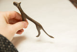Hand holding a slender vintage African bronze cheetah, highlighting its handmade spotted texture.