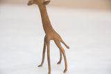Speckled bronze texture on the body and slender legs of a vintage giraffe figurine.