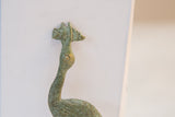 A close-up of the vintage stork sculpture's head, showing its textured oxidized finish.