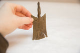 Hand holding a vintage African bronze medallion, showing its scale and textured surface.