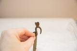 Handcrafted bird head finial with a rustic, aged patina on a vintage bronze medallion.