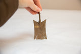 Vintage African bronze bird medallion held to show scale and handmade texture.