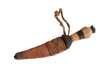 Vintage African dagger with a carved wooden handle and aged patterned leather sheath.