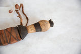 Vintage African dagger's carved wooden handle, dark band, and braided leather details.