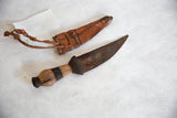 Handmade wooden handle with dark band and rusted blade of the African dagger.