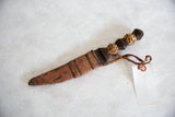 Vintage sheathed dagger with carved cheetah handle and braided leather cord.