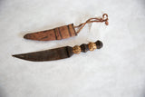 Vintage African dagger with carved cheetah handle shown unsheathed next to its leather sheath.