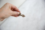 Handheld view of a vintage bronze lizard pendant showing its petite size and smooth finish.