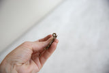 Side profile view of the handmade attachment loop on the bronze lizard pendant.