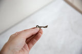 The elongated profile and rustic texture of a small bronze turtle pendant.