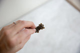 A small dark bronze turtle pendant held in hand to show its scale and texture.