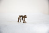 The slender body and smooth back of a vintage bronze monkey figure.