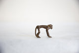 Side profile of the vintage African bronze monkey showing its smooth, arched back.
