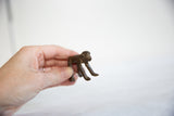 Handmade vintage African bronze monkey held in hand to show its small collectible size.