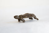 Side view of a vintage bronze turtle showing its textured, circular shell patterns.