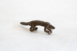Profile view of a vintage African bronze pangolin with detailed scales and curved tail.