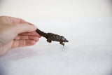 Hand holding vintage dark bronze pangolin, textured scales and curved tail.