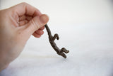 A small, dark bronze pangolin figurine held in a hand to show its scale.