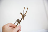 A hand holds a vintage bronze gazelle, showing its handmade texture and light patina.