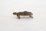Side profile of a handmade bronze turtle showing its weathered texture and spiral patterns.