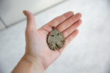 Vintage African bronze jellyfish pendant held in an open palm to show its scale.