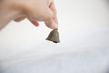 A small vintage African bronze bell held between two fingers to show scale.