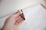 Vintage African bronze tool held to show its small size and rustic, handmade patina.