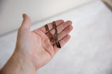 Vintage African bronze tool held in hand to illustrate its small scale.