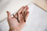 Two handmade African bronze tools in hand showing their small scale and unique variations.