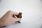 Hand holding a small, dark bronze vintage African owl with aged patina.