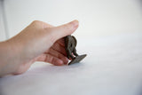 Vintage African bronze owl, held to show its textured back and small flat base.