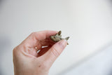 The small scale and textured details of the vintage African bronze fish pendant.