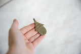 Vintage African bronze hut pendant held in hand, showing its scale and patina.