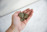 Handmade bronze elephant pendant with a light patina held in a hand for scale.
