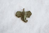 Textured surface and time-softened green patina on a handmade bronze elephant head.