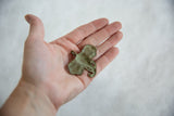 Vintage African bronze elephant pendant with oxidized patina held in hand for scale.