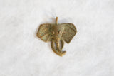Angled view of the vintage elephant pendant's oxidized golden patina and handmade texture.