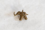 Side view of a vintage bronze elephant pendant showing its coiled wire texture.