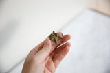 Vintage African bronze elephant pendant held in hand, showing its wire-wrapped design.