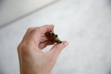 A hand holding the vintage bronze elephant pendant to show its scale and hollow trunk.