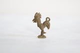 Side profile of a vintage African bronze rooster pendant showing its handmade texture.