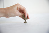 A hand holding the small vintage bronze rooster pendant to show its scale.
