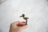 A hand holds the vintage dark bronze crowned stork, showing its small collectible size.