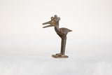 Profile view of a vintage dark bronze African stork showing its crowned head and open beak.
