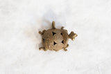 Three-quarters view of a vintage bronze turtle pendant with a geometric wire spiral shell.