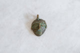 Hand-carved facial details and aged green patina on a vintage bronze mask pendant.