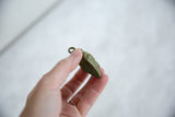 Side profile of the African bronze mask pendant showing its handmade depth and top loop.